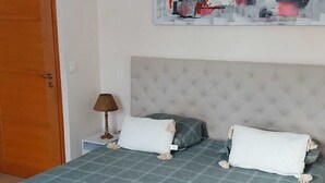 Une chambre à coucher avec un lit, deux oreillers, une table de chevet, une lampe et un tableau au mur.