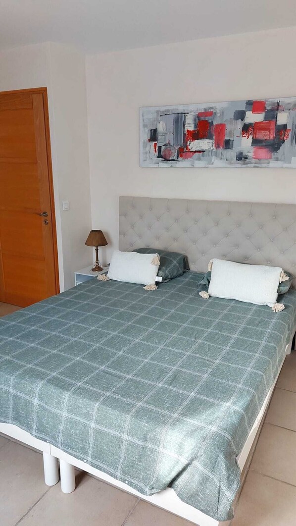 A bedroom with a bed, two pillows, a nightstand, a lamp, and a painting on the wall. - Agreable Maison DE Village Tout Confort (Roaix)