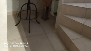 Un petit coin repas avec une table, une chaise et un cadre photo. On y trouve un escalier avec une rampe et une porte qui mène à une autre pièce.