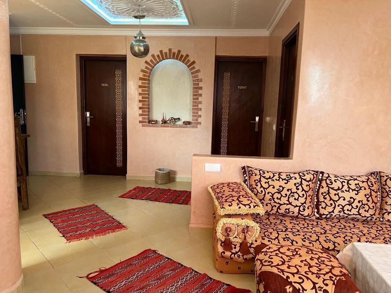 A room with a sofa, a mirror, and two doors labeled 'TATA' and 'TIZNIT'.