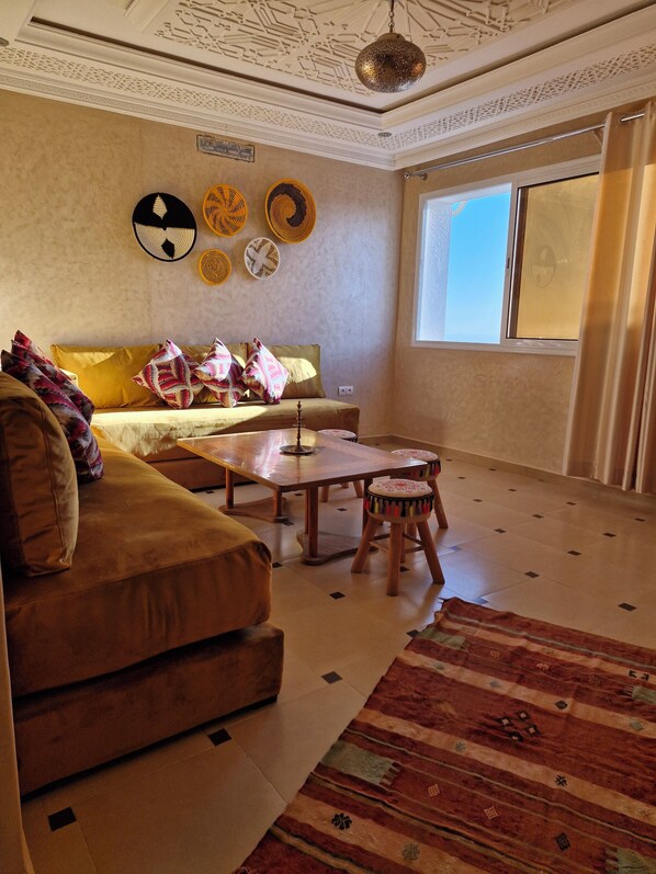 A living room with a sofa, a coffee table, and a patterned rug. - SINIM HOUSE (Taghazout)