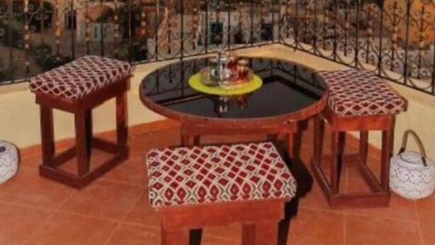 A balcony with a round table and four wooden stools with patterned cushions. - SINIM HOUSE (Taghazout)