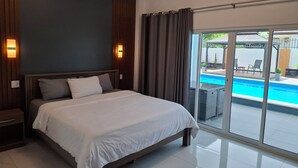 Una habitación de hotel moderna con una cama grande, vista a una piscina y puerta corrediza de vidrio.