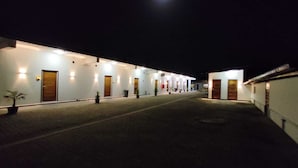 Un pasillo de hotel con varias puertas, cada una iluminada por luces en la pared.