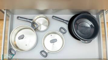 Uma gaveta de cozinha com quatro panelas e uma frigideira.