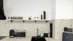 A kitchen with a granite countertop, a coffee maker, a toaster, a sink, and a knife block.
