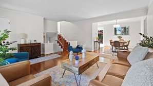 Ein modernes Wohnzimmer mit Couchtisch aus Holz, Ledersofas und einer Treppe, die in einen anderen Raum führt.