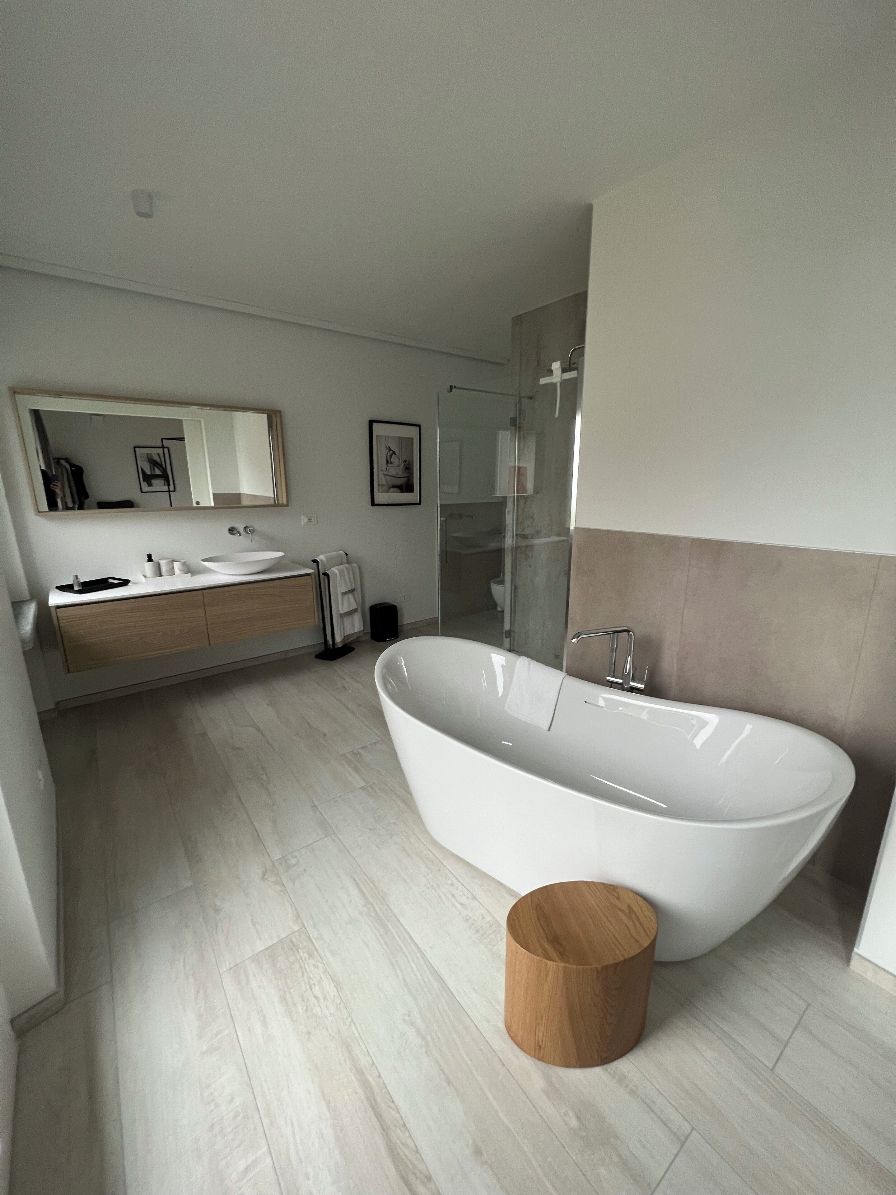 Un bany modern amb una banyera autònoma, un lavabo amb mirall i una zona de dutxa.