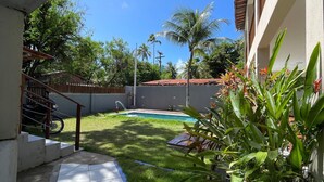 A residential backyard with a swimming pool, a staircase, and a variety of plants. - Pousada Caminho do Paraíso (Ipojuca)