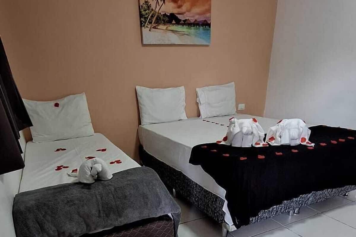 A hotel room with two beds, a small table, and a painting on the wall.