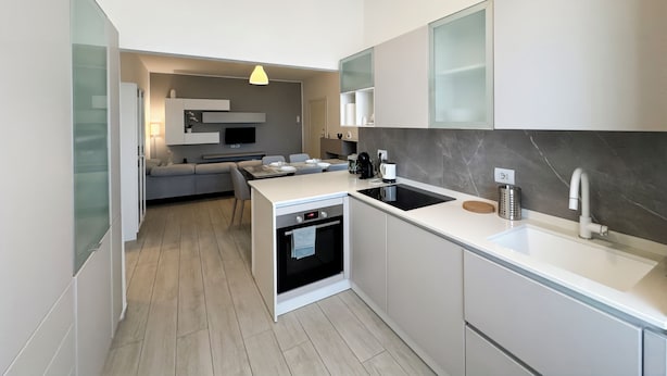 A modern kitchen with integrated appliances, a dining area, and a living space. - Suite Patrizia - Appartamento nel Cuore di Modena (Modena)