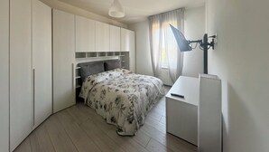 A bedroom with a bed, a desk, a lamp, and a radiator. - Suite Patrizia - Appartamento nel Cuore di Modena (Modena)