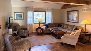 A living room with a wooden ceiling, a television, two sofas, a coffee table, and a lamp. - Coastal Retreat in Angola-by-the-Bay Lewes (Lewes)
