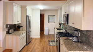 A kitchen with white cabinets, a stainless steel refrigerator, a stove, and a blender. - Coastal Retreat in Angola-by-the-Bay Lewes (Lewes)