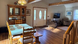 A dining area with a wooden table and chairs, a chandelier, and a wooden cabinet with glass doors. - Coastal Retreat in Angola-by-the-Bay Lewes (Lewes)