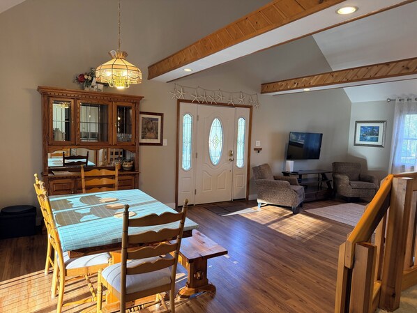 A dining area with a wooden table and chairs, a chandelier, and a wooden cabinet with glass doors.