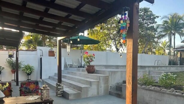 A covered outdoor area with a concrete staircase, outdoor seating, and potted plants.