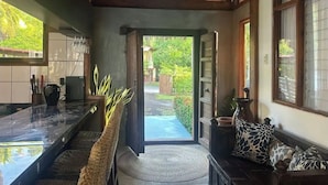 A hallway leading to a garden with a bench and a sofa.