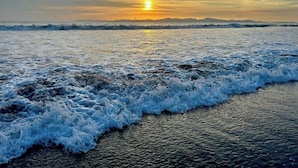 A beach scene with waves and a sunset.