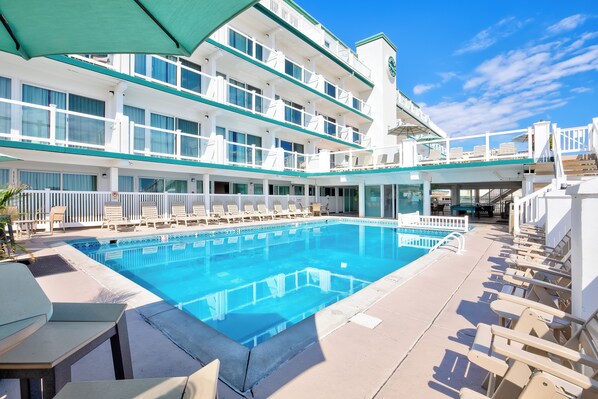 A large indoor swimming pool with multiple lounge chairs and a covered seating area. - Water's Edge Ocean Resort (Wildwood Crest)