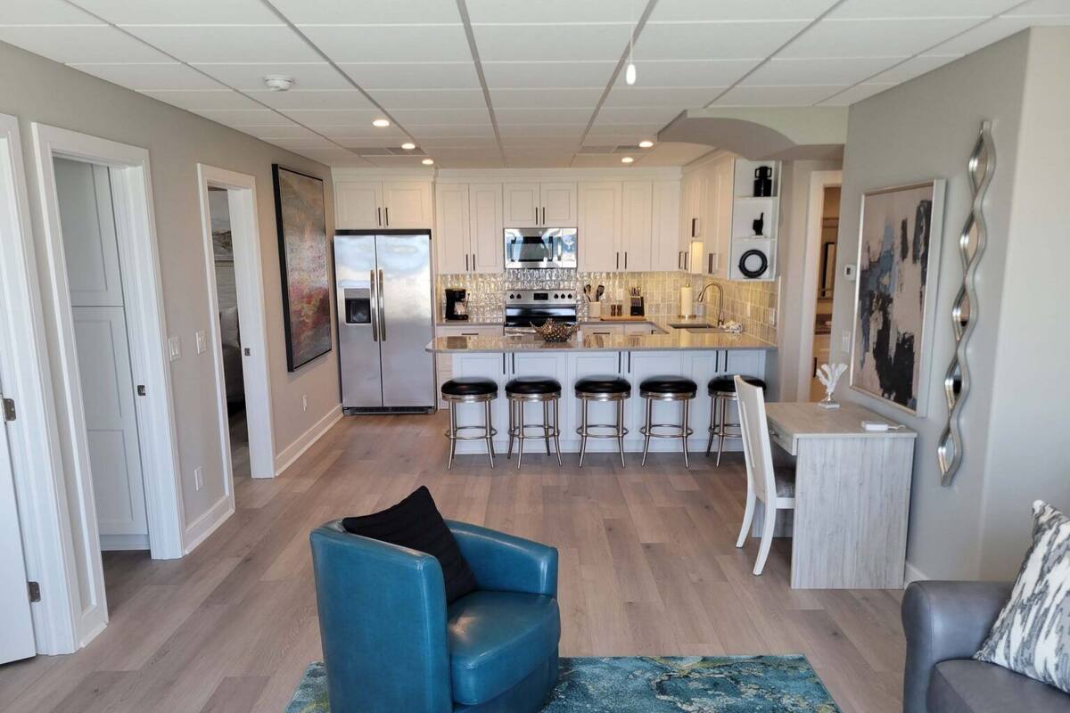 A modern kitchen with white cabinets, stainless steel appliances, and a central island with bar stools.