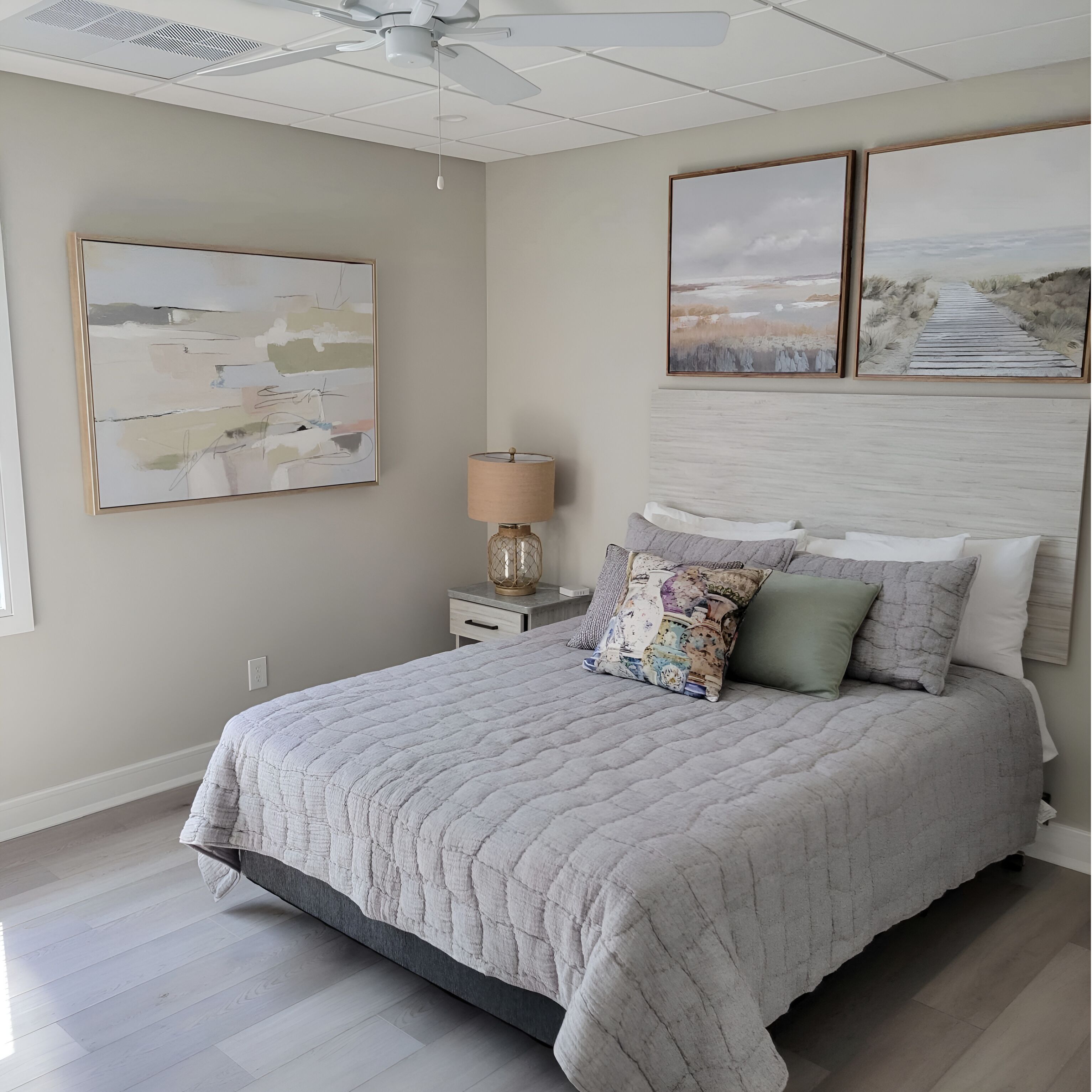 A bedroom with a bed, a nightstand, a lamp, and wall art.