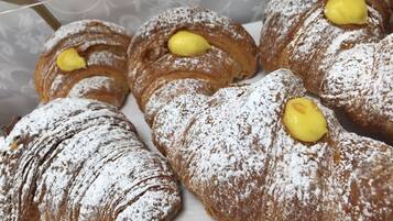A selection of pastries, including croissants and cream puffs, dusted with powdered sugar.