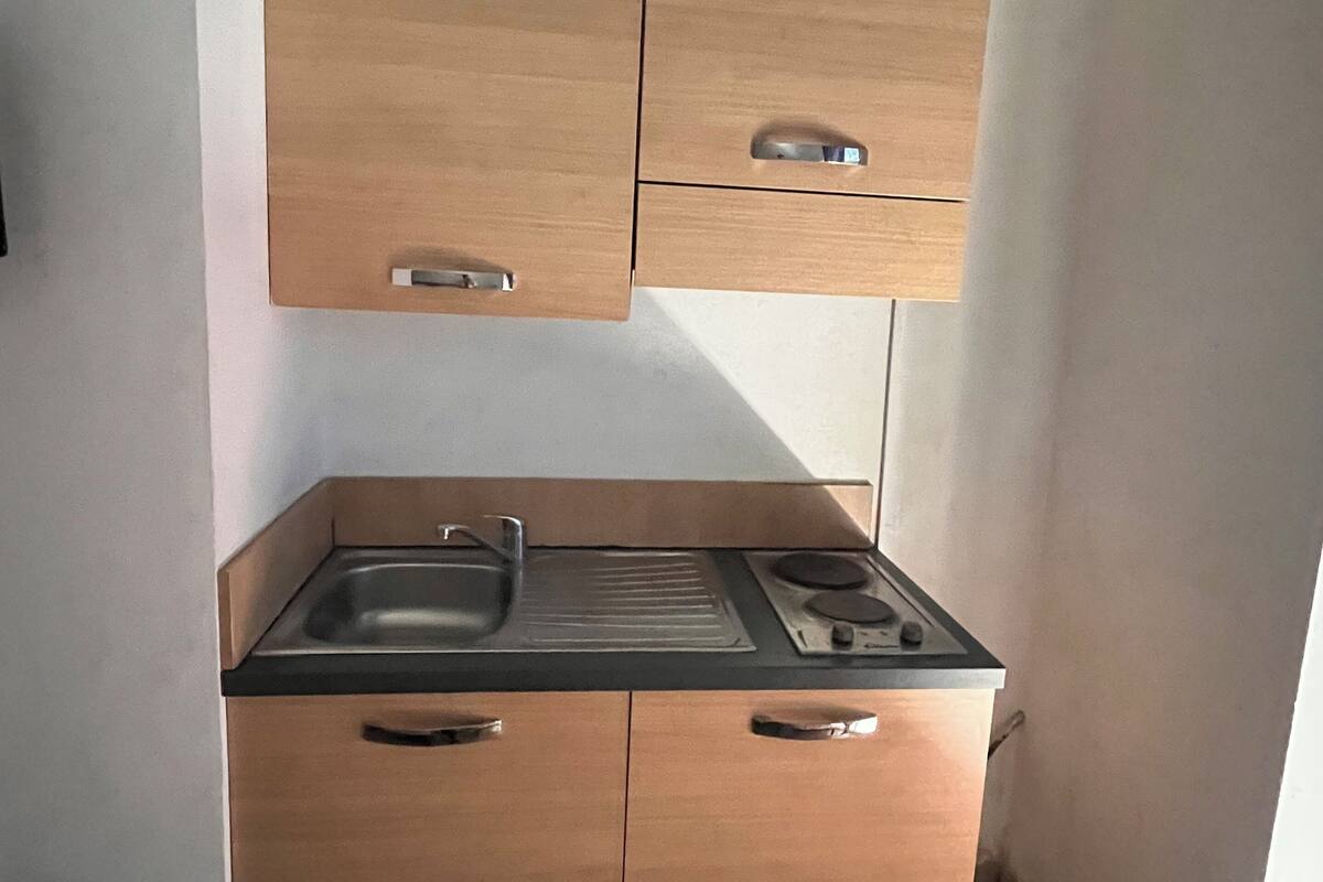 A compact kitchen with wooden cabinets, a sink, and a stove.
