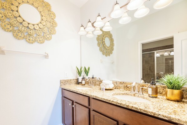 A bathroom with two sinks, a large mirror, decorative wall sconces, and a potted plant. - The World of Wonders Residence | Minutes from the Magic, Miles Ahead of the Rest (Four Corners)