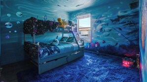 Quarto com beliche, janela e um mural com tema marinho na parede.