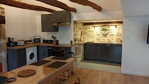 Une cuisine compacte dotée d’appareils électroménagers modernes, d’un mur d’accent en pierre et de poutres apparentes.