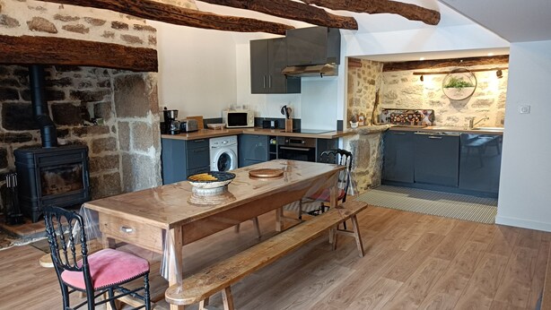 Une cuisine rustique avec un mur en pierre, des poutres en bois et un poêle encastré.