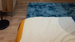 A bedroom with a sloped ceiling, a stone wall, a wooden dresser, a blue rug, and a skylight.