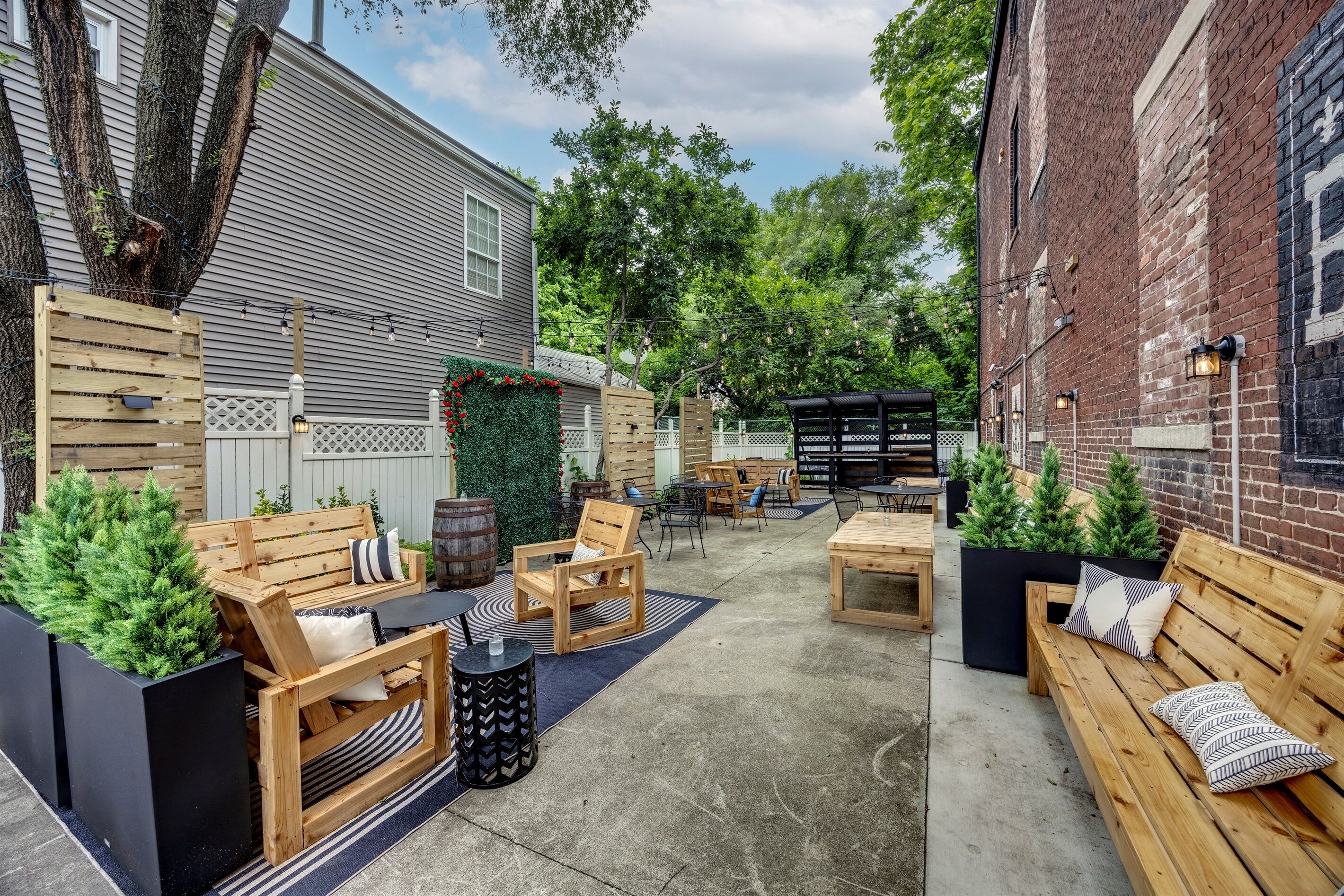 Un espace patio am énagé avec des meubles en bois, des jardinières remplies de plantes et un mur en briques.