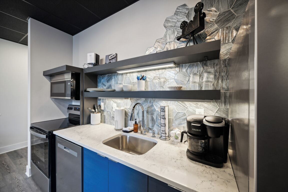 A modern kitchen with a stainless steel sink, a coffee maker, and a microwave.