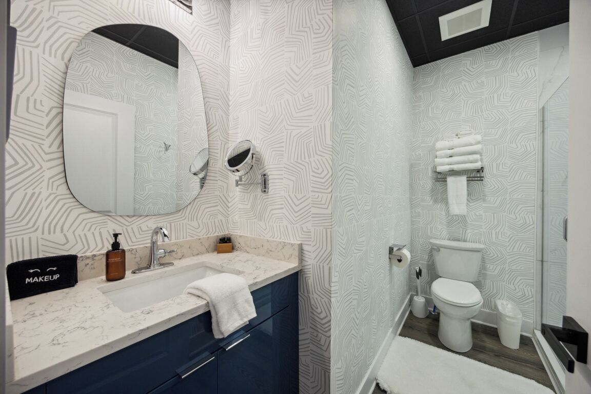 A modern bathroom with a vanity, sink, mirror, and toilet.