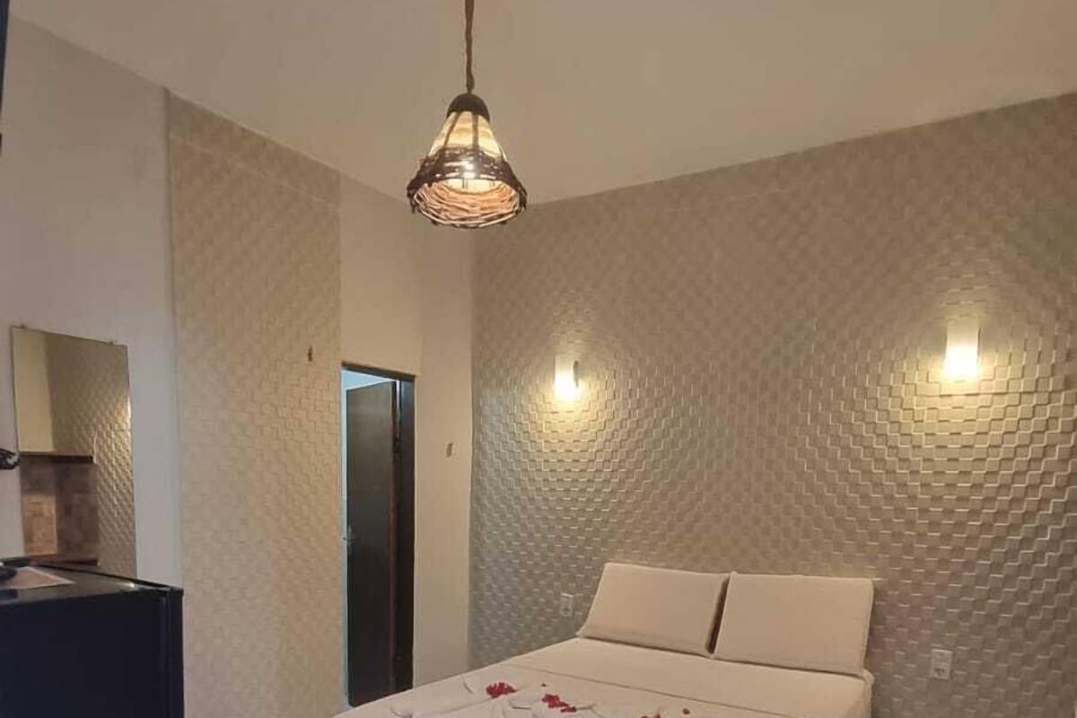 Un dormitorio con una cama, un escritorio y una lámpara colgante.