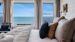 Een slaapkamer met een groot bed, een stoel en uitzicht op zee.