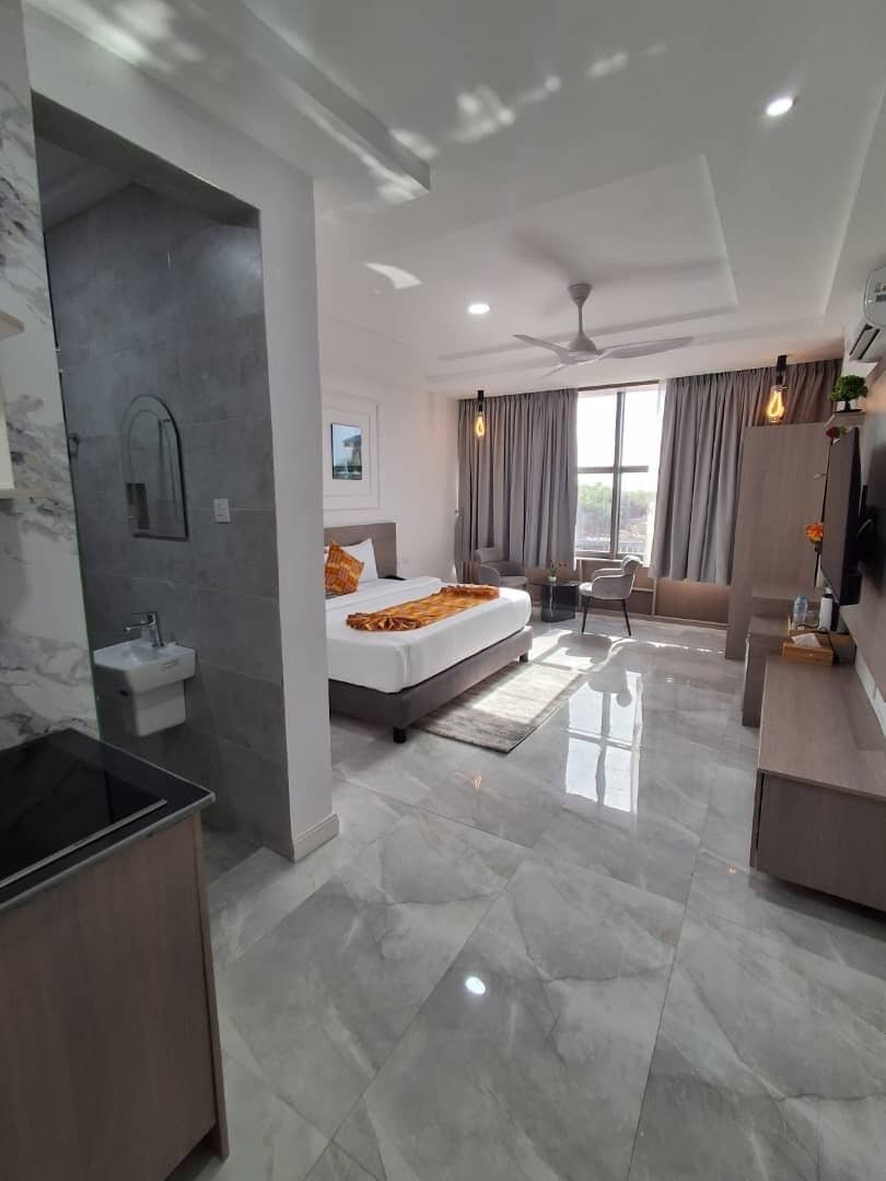 A modern hotel room with a bed, a desk, a vanity, and a bathroom.