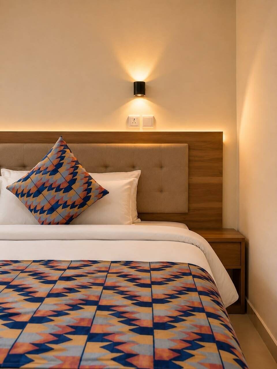 Cama bem arrumada com colcha estampada e uma almofada decorativa.