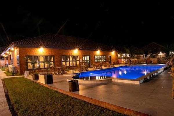 Una piscina al aire libre, sombrillas, sillones reclinables de piscina