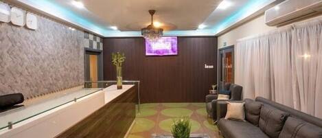 A reception area with a reception desk, a sofa, a coffee table, and a television.