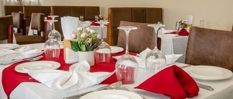 A dining area with tables set for a meal, featuring white plates, cutlery, and glassware.
