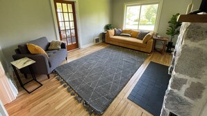 A living room with a sofa, a coffee table, a rug, and a fireplace.