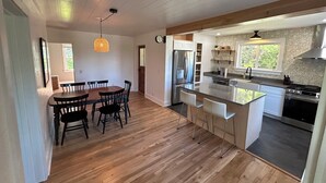 A modern kitchen with a central island, wooden flooring, and built-in appliances.