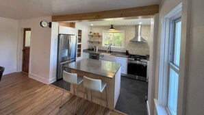 A modern kitchen with a central island, stainless steel appliances, and a window providing natural light.