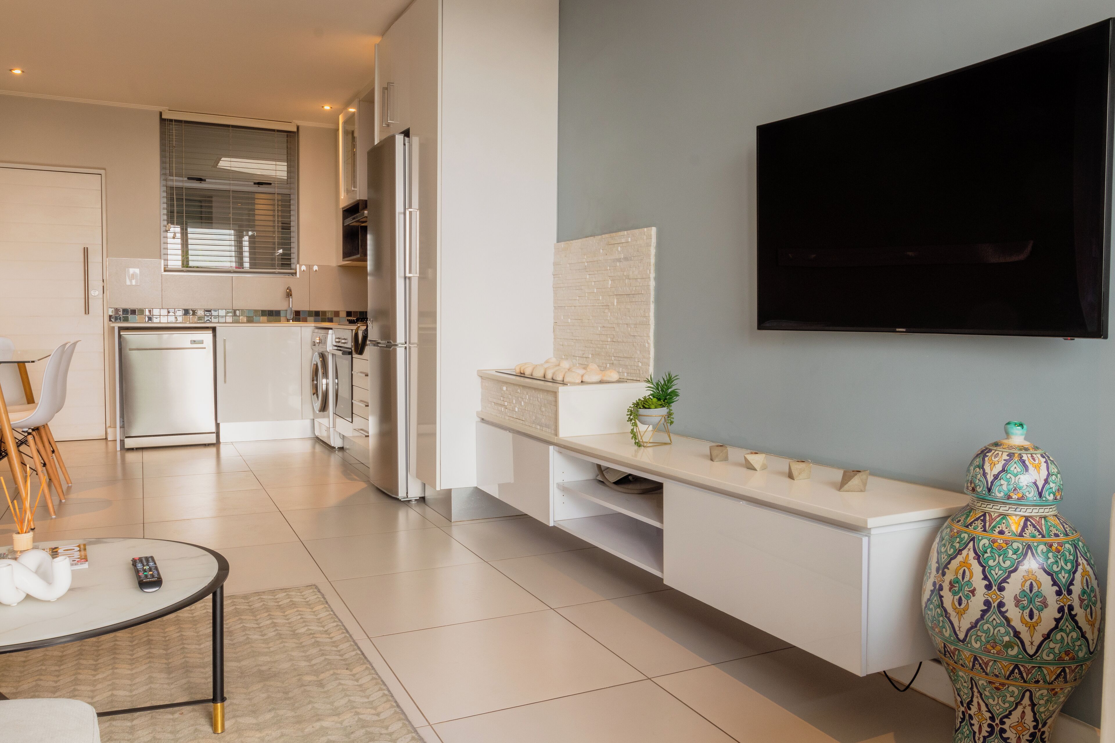 A modern kitchen with white cabinetry, a built-in oven, and a large window.