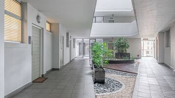 Een moderne hotelgang met dakraam, potplanten en een betegelde vloer.