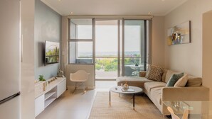 A modern living room with a sofa, coffee table, and a TV mounted on the wall. - KMG Apartments at The Apex on Smuts  (Johannesburg)