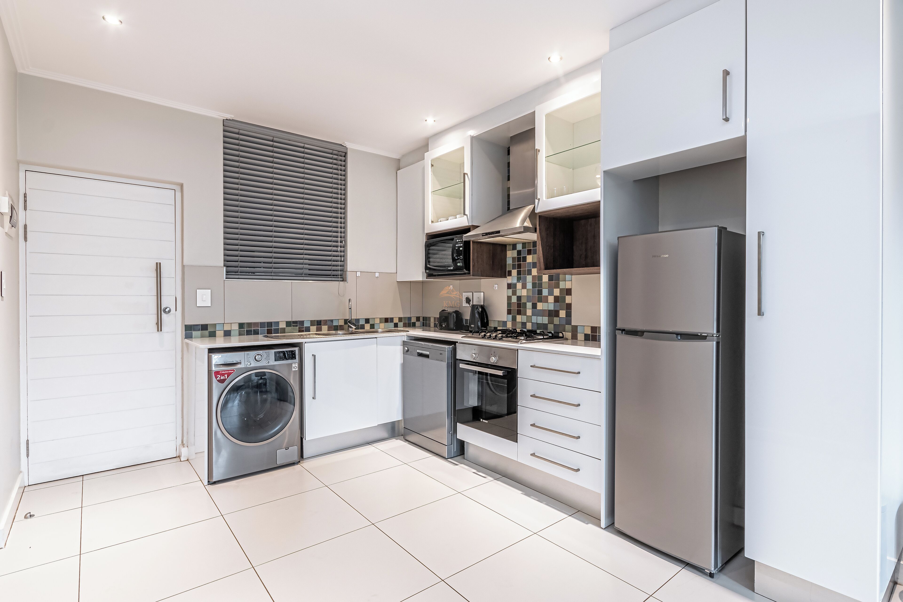 Eine moderne Küche mit Waschmaschine, Geschirrspüler, Backofen und Kühlschrank.